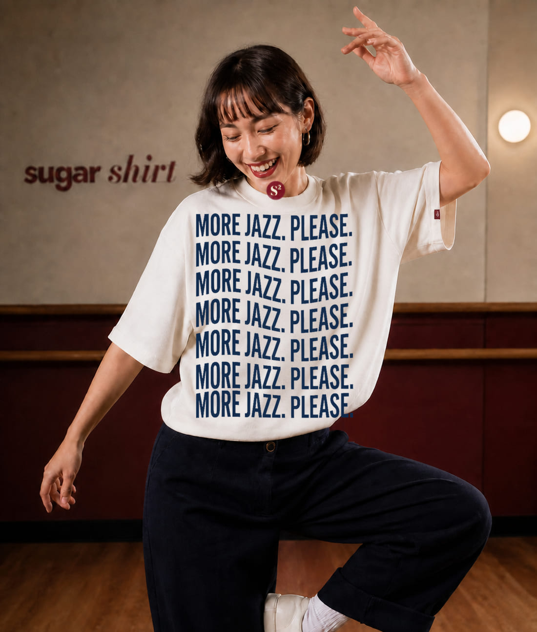 Ballerina di solo jazz a metà movimento con il braccio alzato, indossa la t-shirt More Jazz. Please. crema