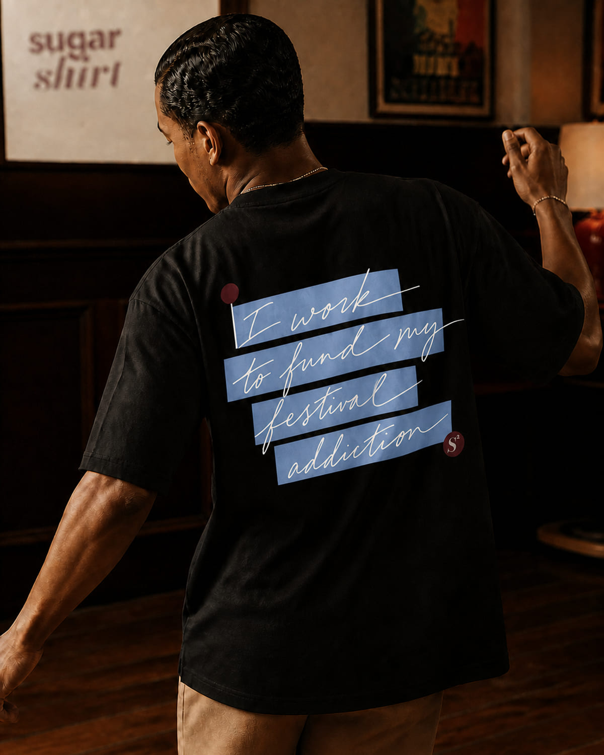 T-shirt oversize nero con la frase «I work to fund my festival addiction» scritta a mano su evidenziatore azzurro